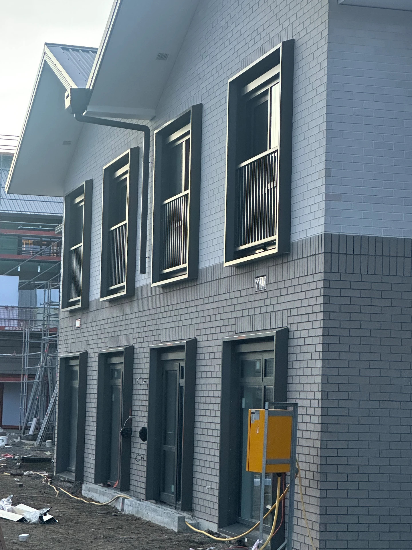Two-storey brick build with dark window and door joinery on a Wellington construction site